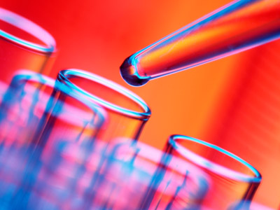 AdobeStock_172980875_sm Pipette tropft Flüssigkeit in ein Reagenzglas vor rotem Hintergrund